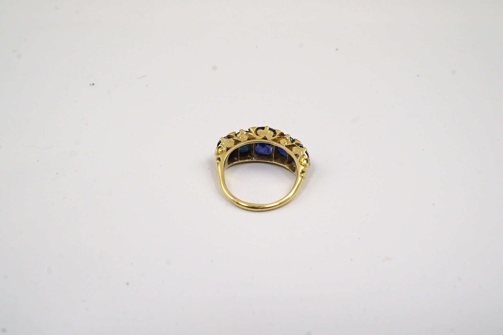 An Edwardian gold and graduated five stone oval cut sapphire set half hoop ring